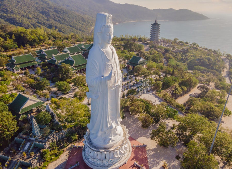 해안 반도 언덕 위 거대한 흰색 해수관음상과 사찰 전경 및 바다 조망