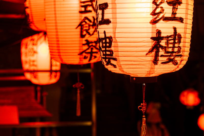 어둠 속에서 은은한 붉은빛을 내뿜으며 매달려 있는 전통 한자 적힌 홍등