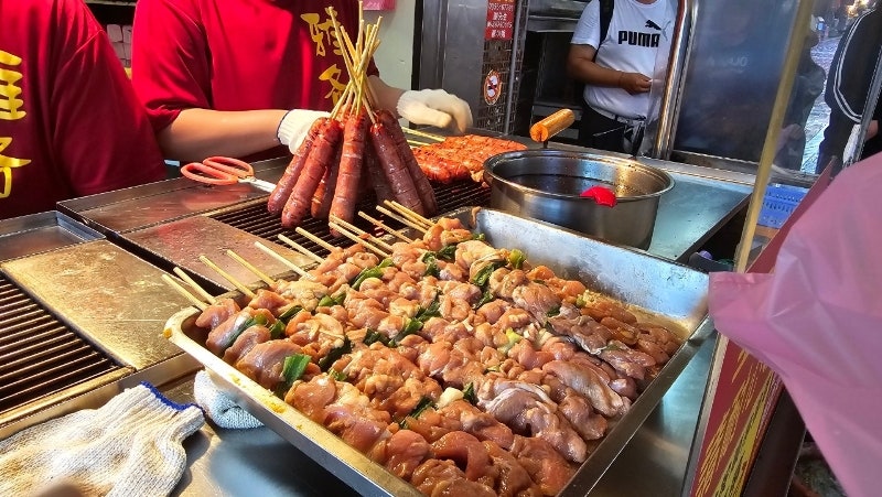 노점 매대 위에 진열된 고기 꼬치와 소시지 꼬치 구이