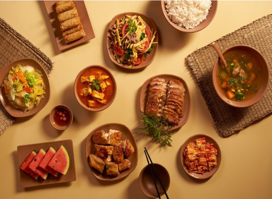 테이블 위에 춘권, 볶음 요리, 고기 요리, 국, 밥, 수박 등이 토속적인 그릇에 담겨 차려진 상차림입니다.