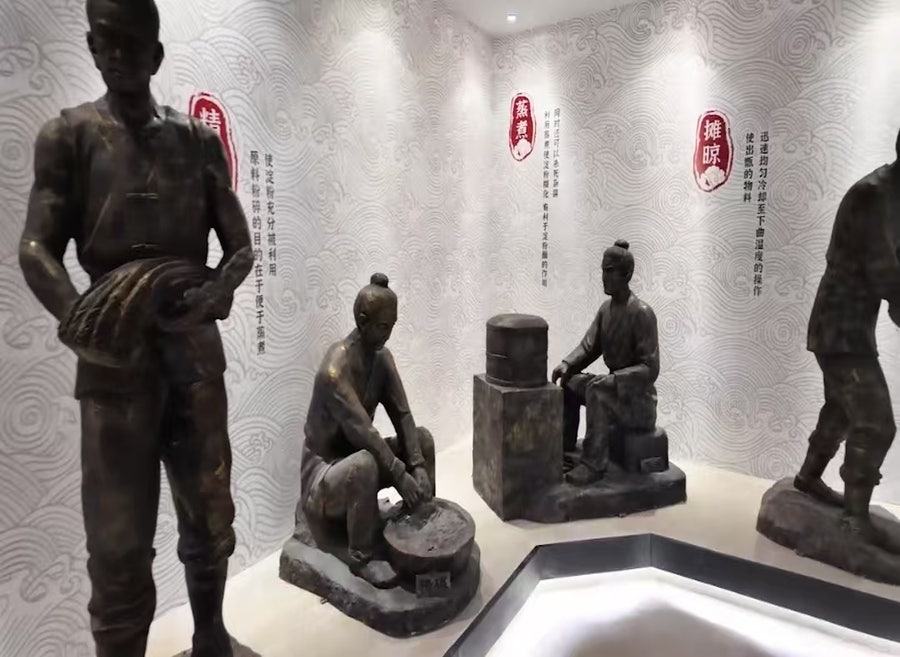 옛 전통 복장을 한 인물들이 양조 작업을 하는 모습을 표현한 청동 조각상 전시