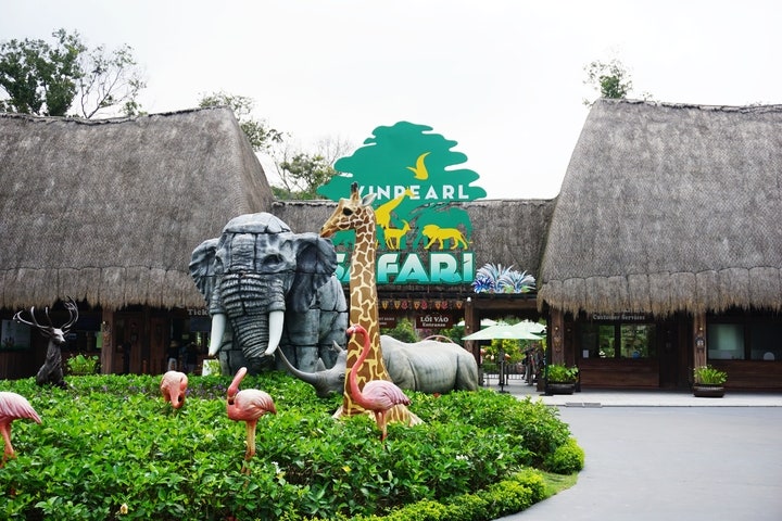기린, 코끼리, 플라밍고 등 대형 동물 조형물과 VINPEARL SAFARI 영문 간판이 세워진 초가 지붕 입구