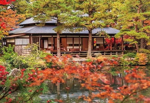 붉은 단풍나무와 고요한 연못 수면 뒤편에 자리한 고즈넉한 전통 목조 주택