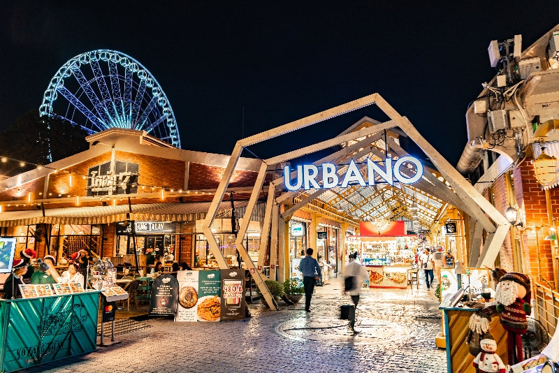 대형 대관람차가 올려다보이는 야경 속 아치형 게이트 'URBANO'와 쇼핑몰 보행로