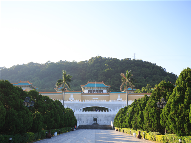 산 아래 넓은 진입로와 정원수 뒤로 보이는 푸른 지붕의 대형 박물관 본관