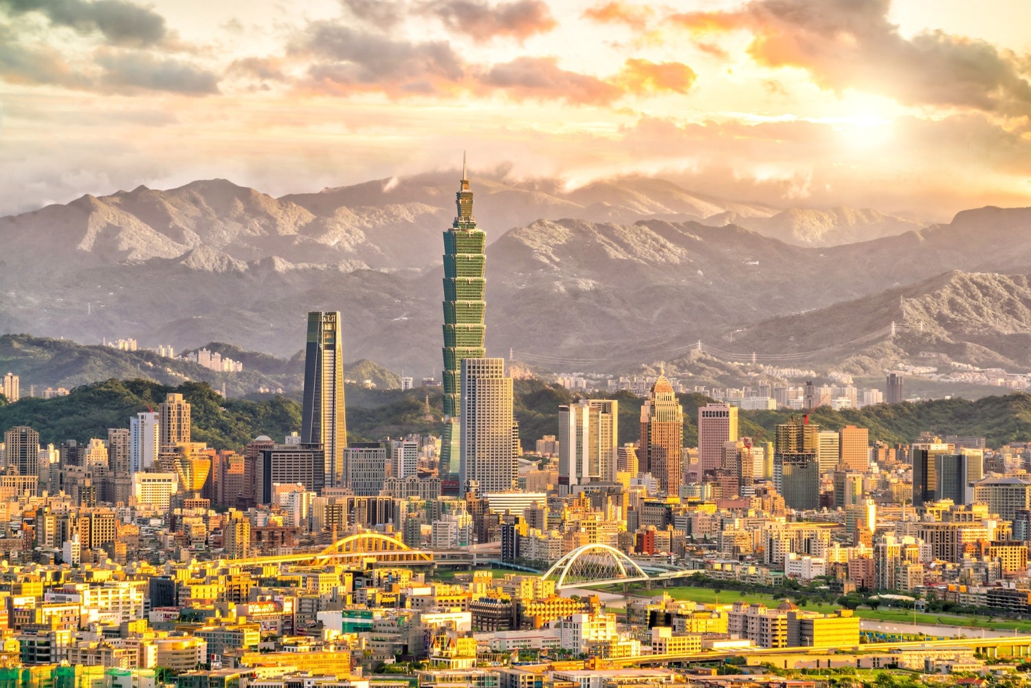 황금빛 노을빛을 받는 도시 전경과 멀리 산세를 배경으로 높게 솟은 타이베이 101빌딩 중심의 전경