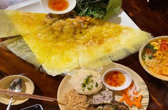 노란색 크레페 형태의 베트남식 부침개 반쎄오와 밥, 고기, 국수가 차려진 식탁